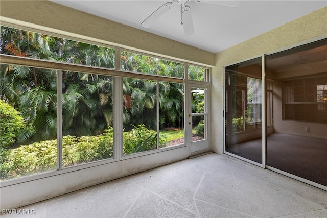 unfurnished sunroom featuring a ceiling fan and a wealth of natural light