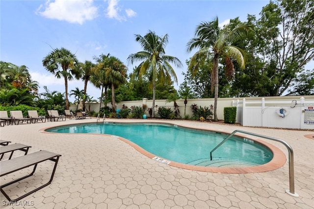 community pool with a patio area and fence