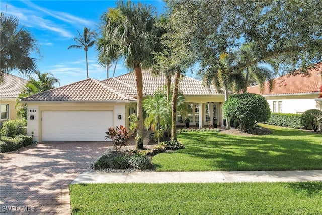 view of front of house featuring decorative driveway, stucco siding, a front yard, a garage, and a tiled roof