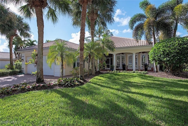 mediterranean / spanish-style home featuring a garage, a tile roof, driveway, stucco siding, and a front yard