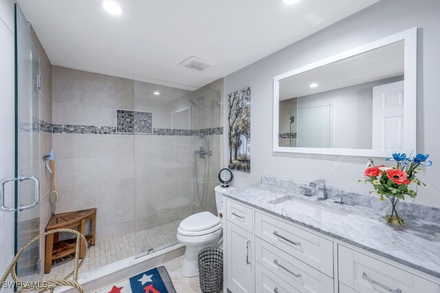 bathroom with tile patterned flooring, a shower with door, vanity, and toilet