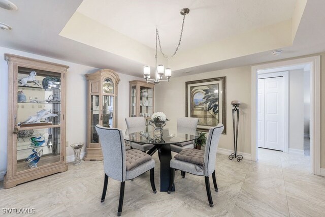 tiled dining space with a raised ceiling and a chandelier