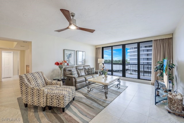 tiled living room featuring ceiling fan and floor to ceiling windows