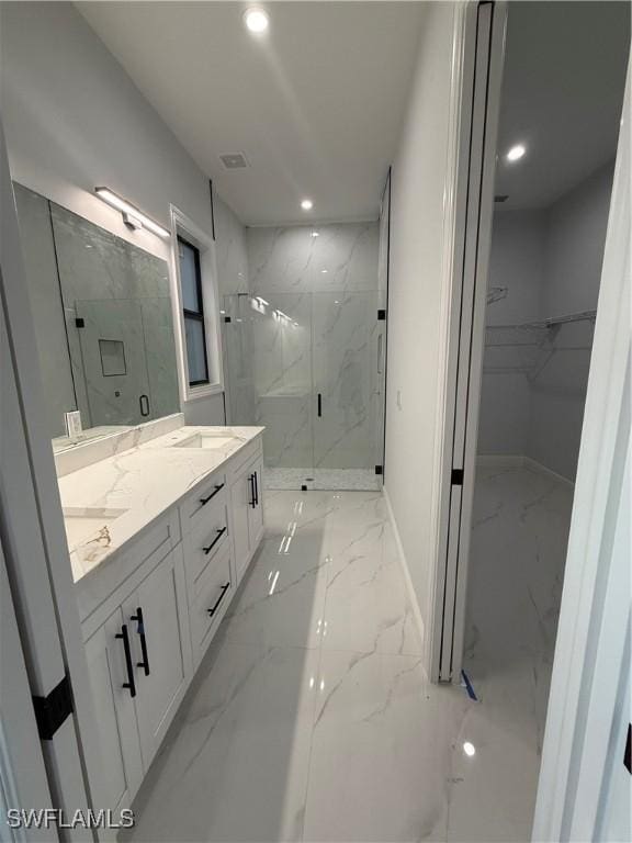 bathroom with recessed lighting, marble finish floor, a marble finish shower, double vanity, and a walk in closet