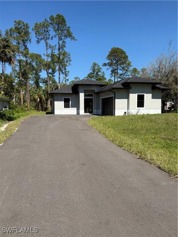 view of front facade featuring a garage, aphalt driveway, and stucco siding