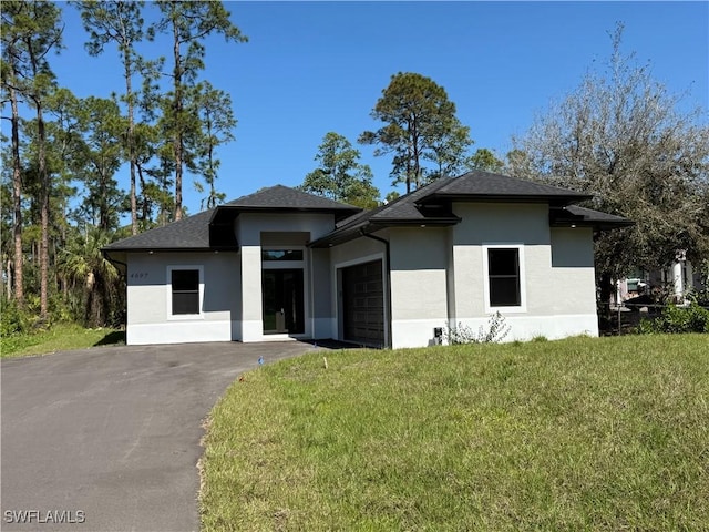 prairie-style house featuring aphalt driveway, roof with shingles, stucco siding, an attached garage, and a front lawn