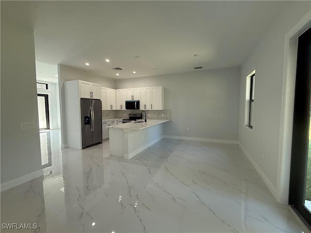 kitchen featuring stainless steel appliances, a peninsula, white cabinets, marble finish floor, and tasteful backsplash