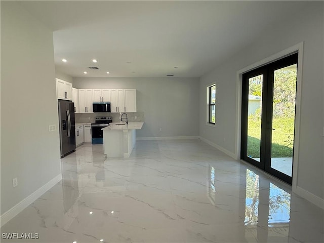 kitchen with stainless steel appliances, light countertops, open floor plan, white cabinetry, and a sink