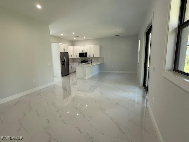 kitchen featuring white cabinetry, baseboards, open floor plan, light countertops, and appliances with stainless steel finishes