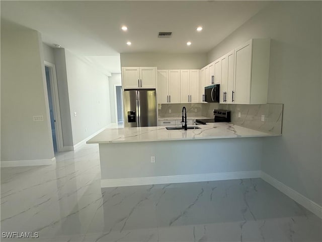 kitchen with a peninsula, a sink, visible vents, white cabinets, and appliances with stainless steel finishes