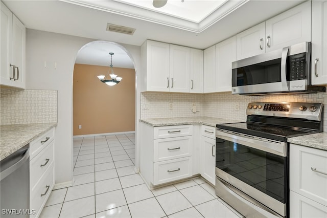 kitchen featuring a notable chandelier, backsplash, stainless steel appliances, white cabinetry, and light tile patterned flooring