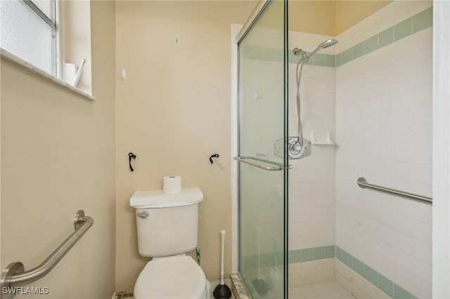 bathroom with a shower with shower door and toilet