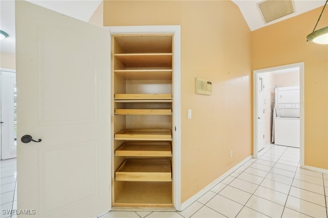 interior space with lofted ceiling, stacked washer and clothes dryer, and light tile patterned floors