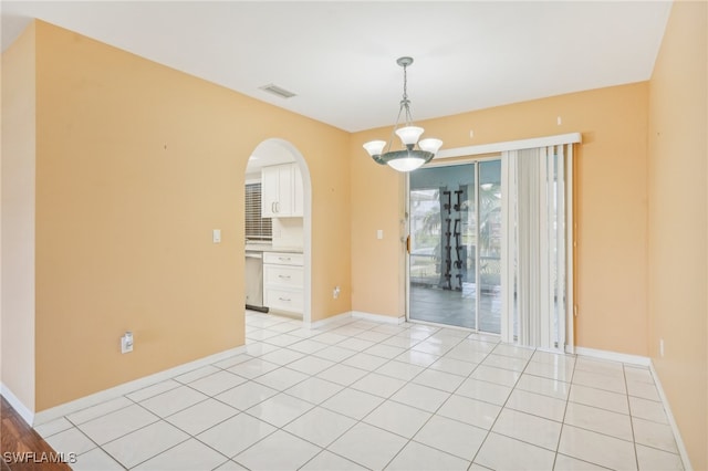 spare room featuring light tile patterned floors and a chandelier