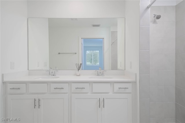 bathroom with a tile shower and vanity