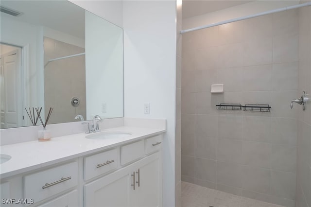 bathroom with tiled shower and vanity