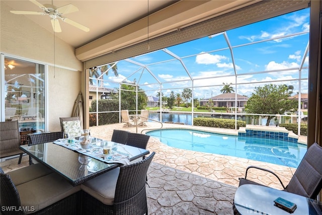 outdoor pool with glass enclosure, a patio, a ceiling fan, outdoor dining area, and a water view