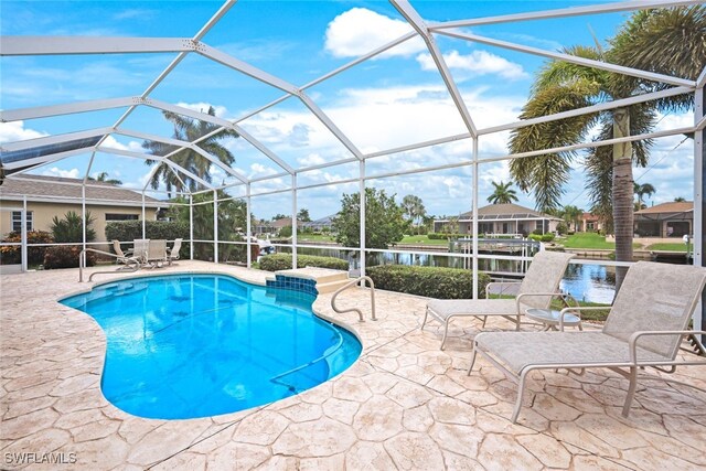 view of pool with glass enclosure, a patio area, and a water view