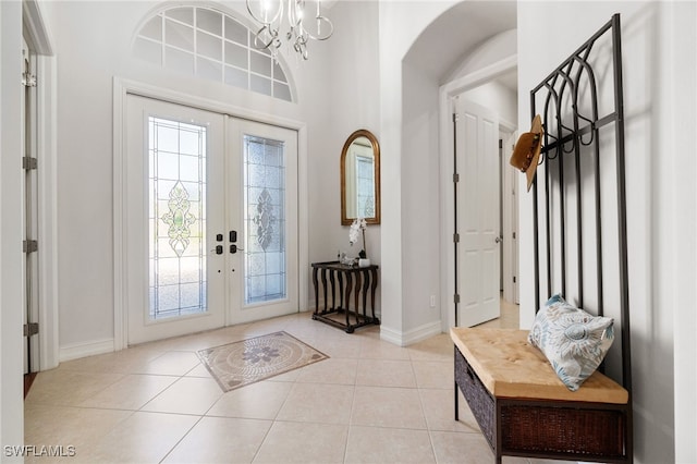 tiled foyer with a high ceiling, french doors, and a notable chandelier