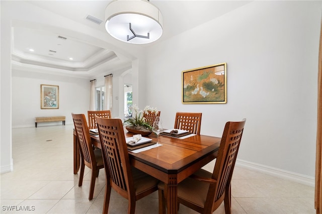 dining room with a tray ceiling and light tile patterned floors