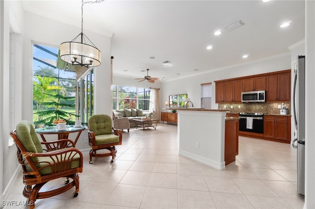 kitchen with appliances with stainless steel finishes, light tile patterned floors, ornamental molding, and pendant lighting