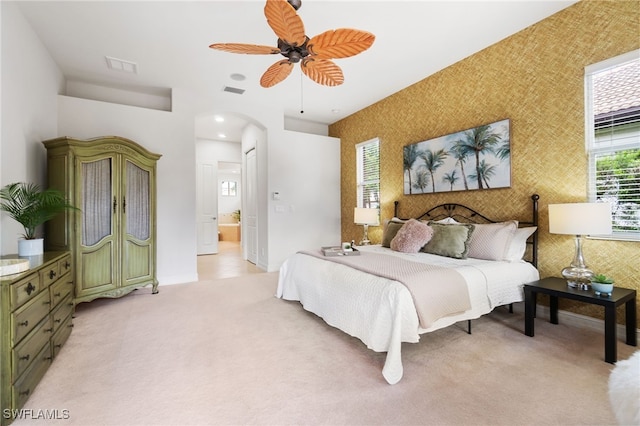 bedroom featuring ceiling fan, light carpet, and ensuite bathroom