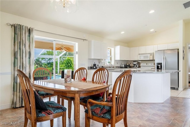 dining room with light tile patterned flooring and vaulted ceiling