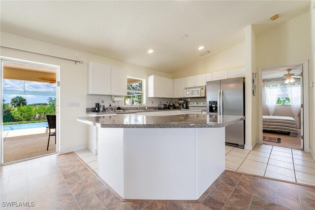 kitchen featuring white cabinetry, plenty of natural light, a center island, and white appliances