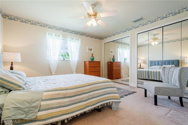 bedroom with light carpet, two closets, and ceiling fan