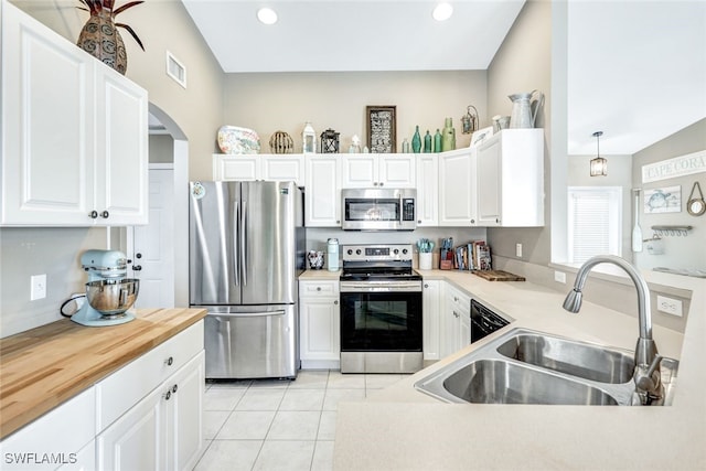 kitchen featuring decorative light fixtures, lofted ceiling, stainless steel appliances, and white cabinets