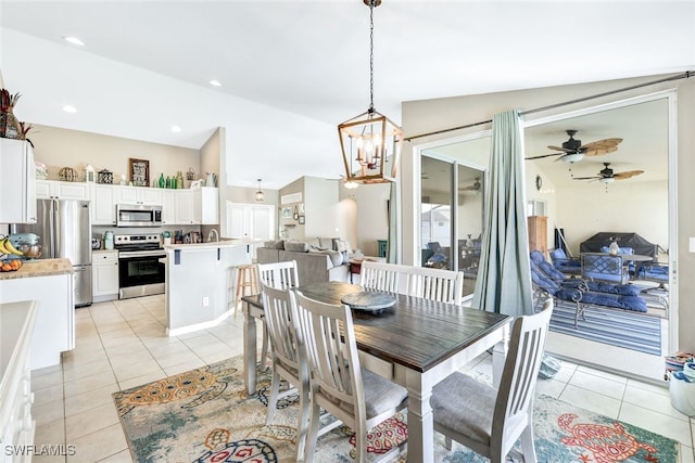 tiled dining room with ceiling fan with notable chandelier and vaulted ceiling