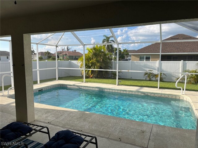 view of swimming pool with a lawn, glass enclosure, and a patio area