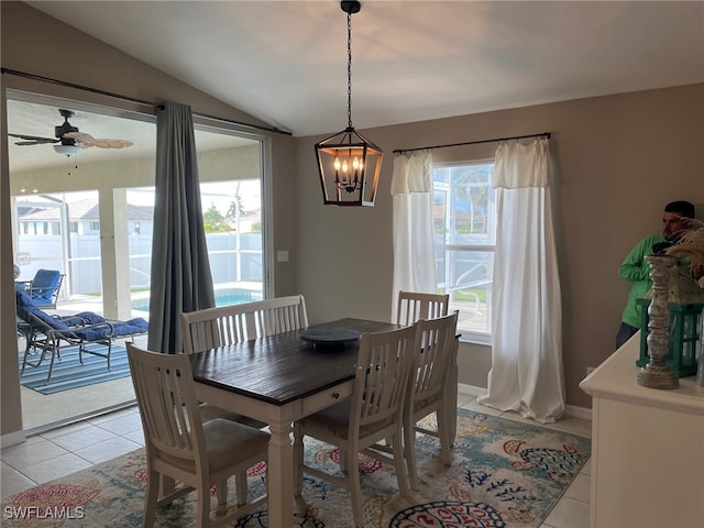 dining room with ceiling fan with notable chandelier, lofted ceiling, and light tile patterned floors