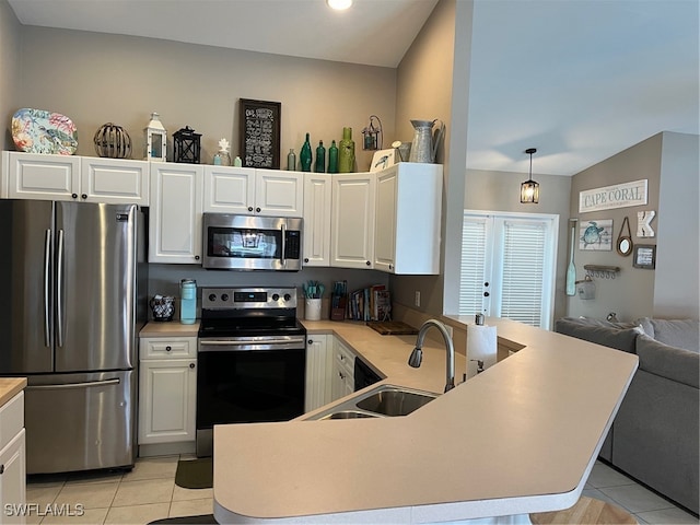 kitchen with pendant lighting, sink, kitchen peninsula, appliances with stainless steel finishes, and vaulted ceiling