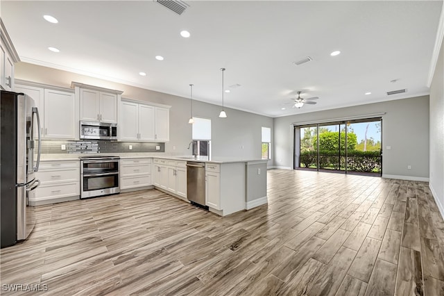 kitchen with kitchen peninsula, white cabinetry, ceiling fan, stainless steel appliances, and pendant lighting