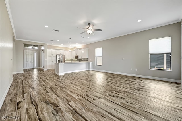 unfurnished living room featuring light hardwood / wood-style flooring, ceiling fan, and crown molding