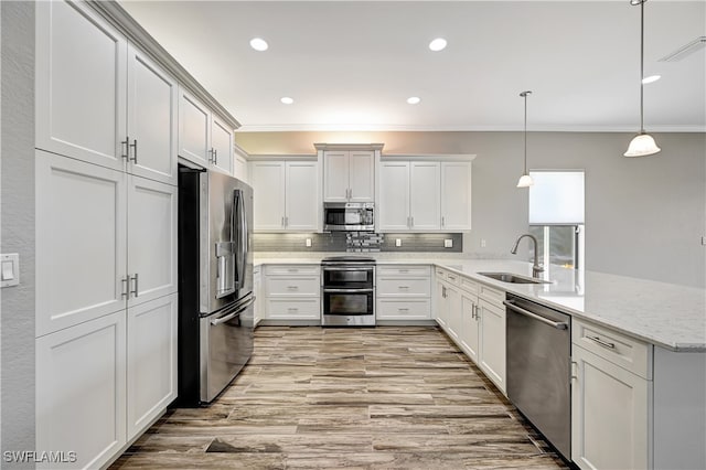 kitchen featuring appliances with stainless steel finishes, sink, decorative light fixtures, white cabinets, and crown molding