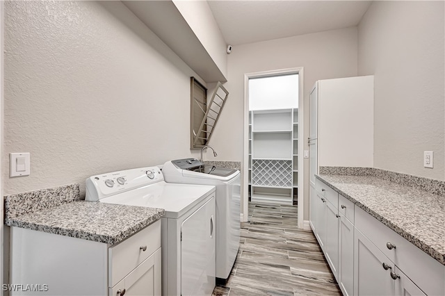 washroom with independent washer and dryer, light wood-type flooring, and cabinets