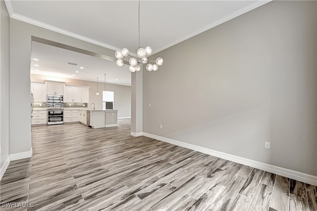 unfurnished living room featuring crown molding, a notable chandelier, and light hardwood / wood-style floors