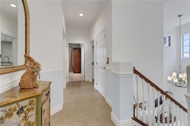 corridor featuring a chandelier, light tile patterned flooring, recessed lighting, a sink, and ornamental molding