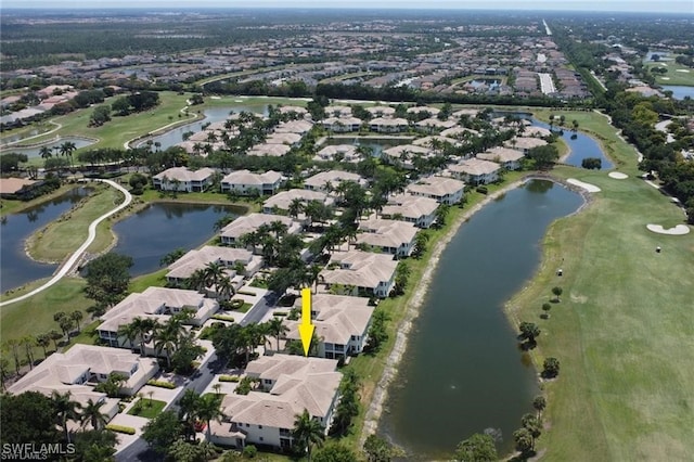 drone / aerial view featuring golf course view, a water view, and a residential view