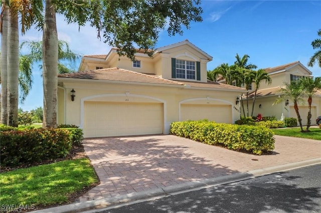 mediterranean / spanish home with a tile roof, decorative driveway, and stucco siding