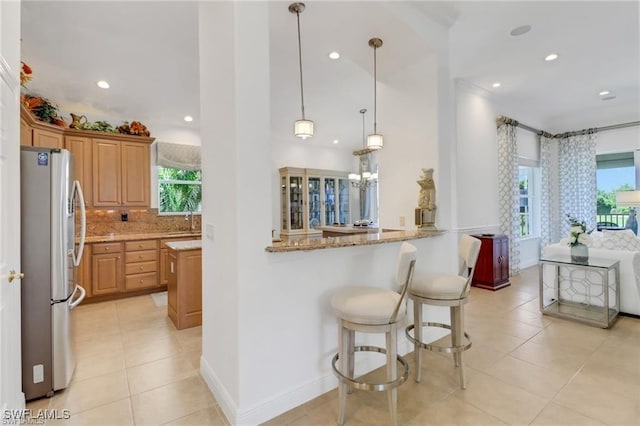 kitchen with a healthy amount of sunlight, light stone countertops, and freestanding refrigerator