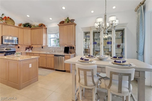 kitchen with a center island, a sink, stainless steel appliances, light brown cabinets, and backsplash