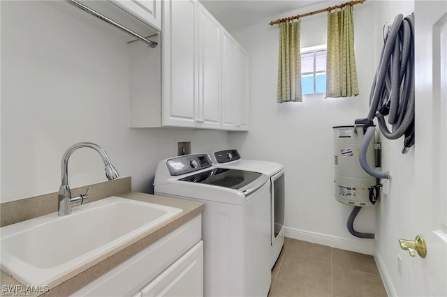 clothes washing area with light tile patterned floors, cabinet space, a sink, washer and dryer, and baseboards