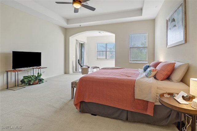 bedroom with a raised ceiling, ceiling fan, and carpet floors