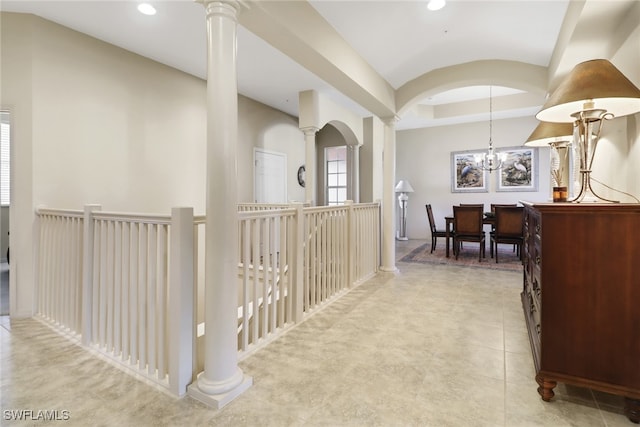 hallway with ornate columns, light tile patterned floors, and a notable chandelier