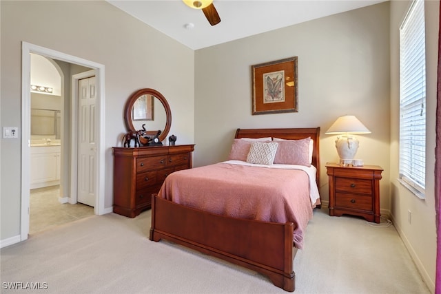 bedroom featuring connected bathroom, light carpet, and ceiling fan