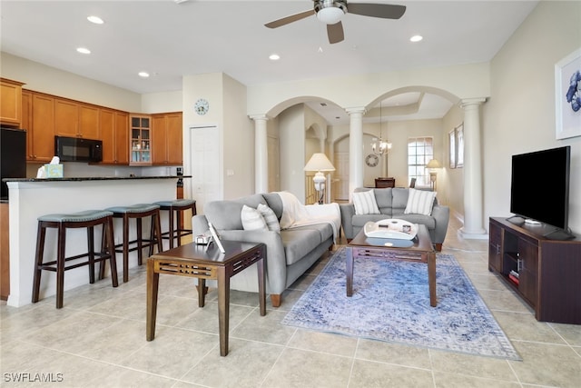 living room featuring ceiling fan with notable chandelier, decorative columns, and light tile patterned flooring