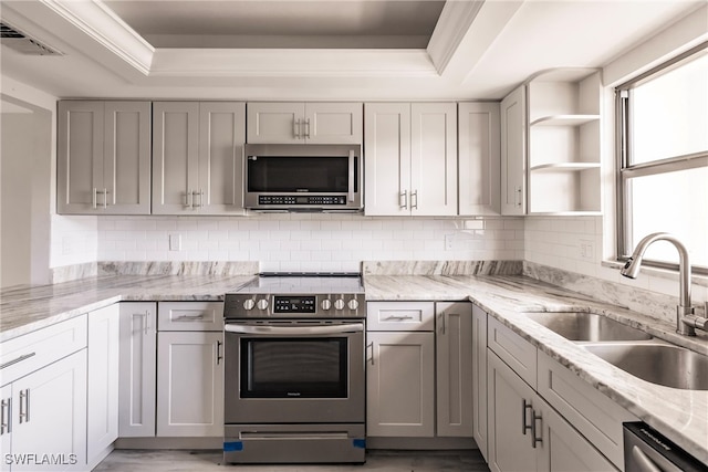 kitchen with stainless steel appliances, a raised ceiling, tasteful backsplash, and sink